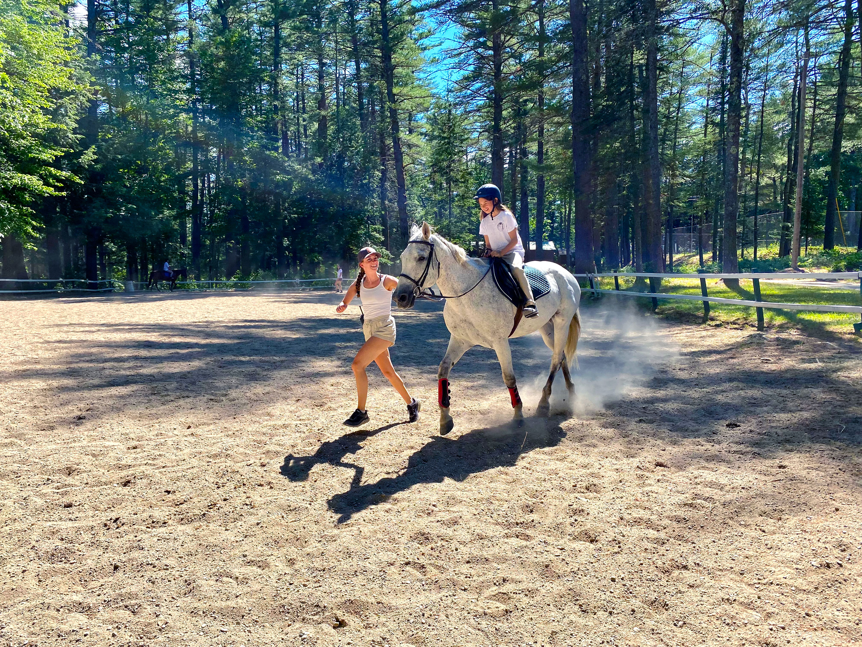 A young camper rides a white horse for the first time.
