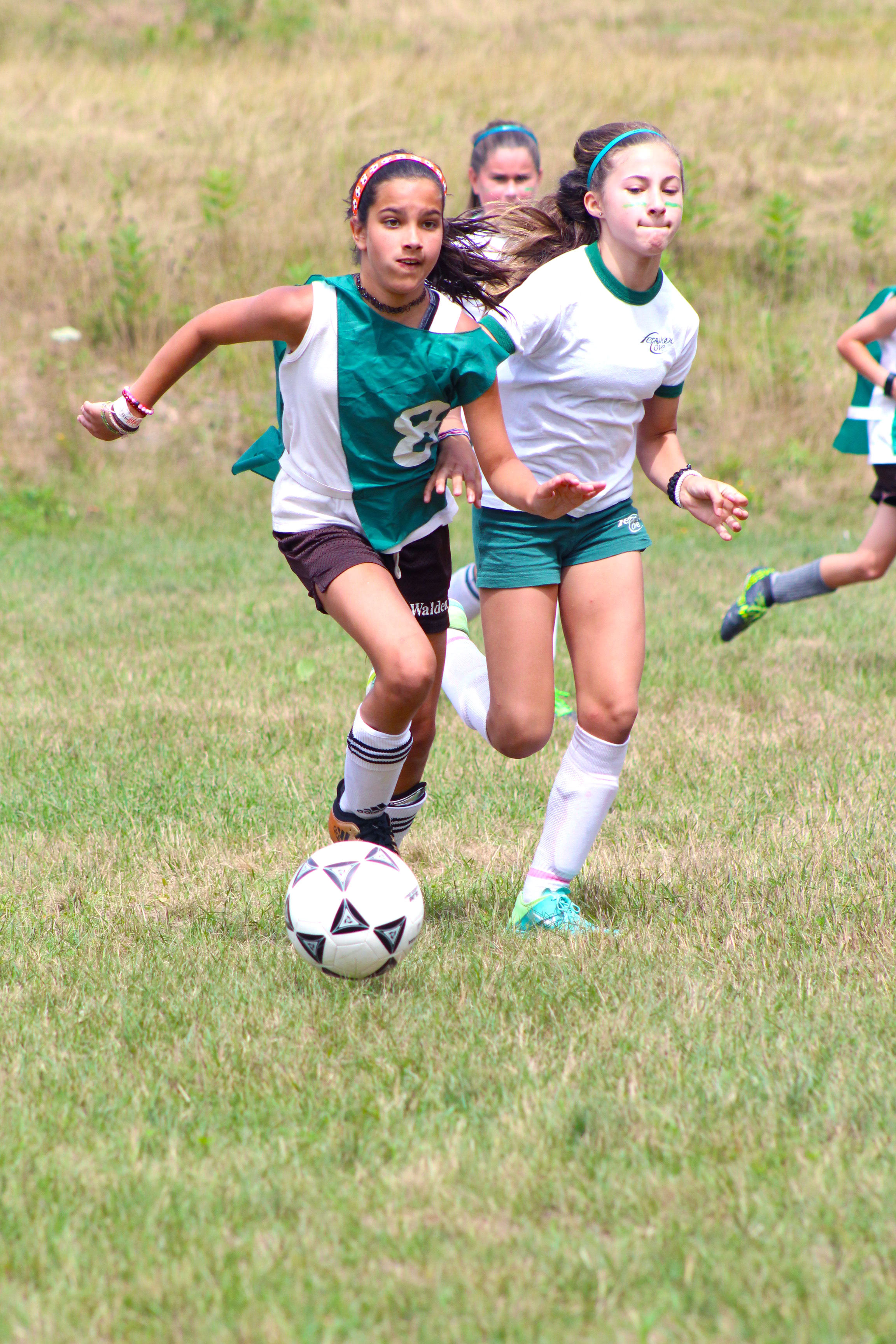 Two young campers play soccer together on a field.