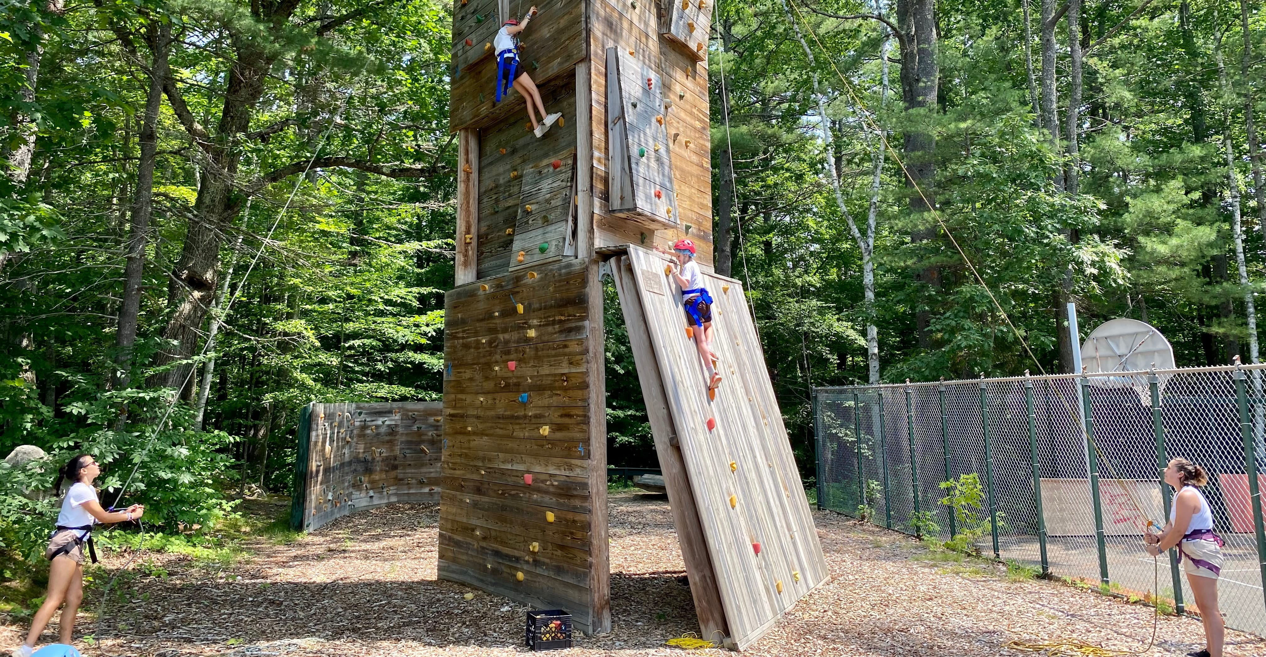 Camp Walden staff members assist campers on the climbing wall.
