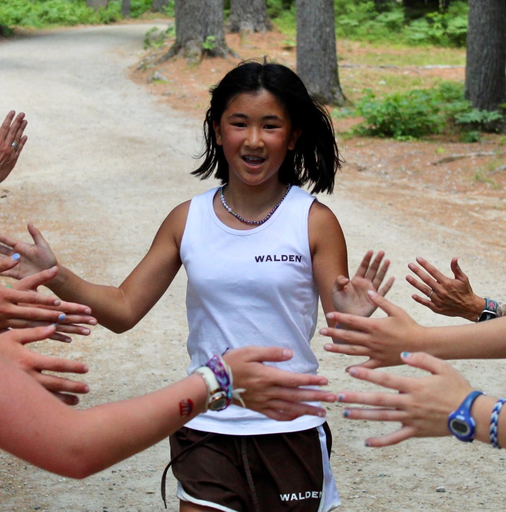 A Camp Walden camper high-fives with her teammates