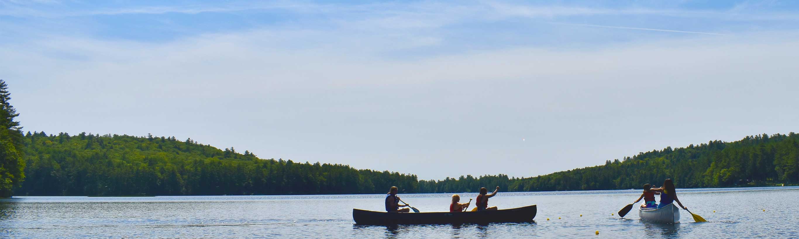 A panoramic scene with canoes and hills in the background.