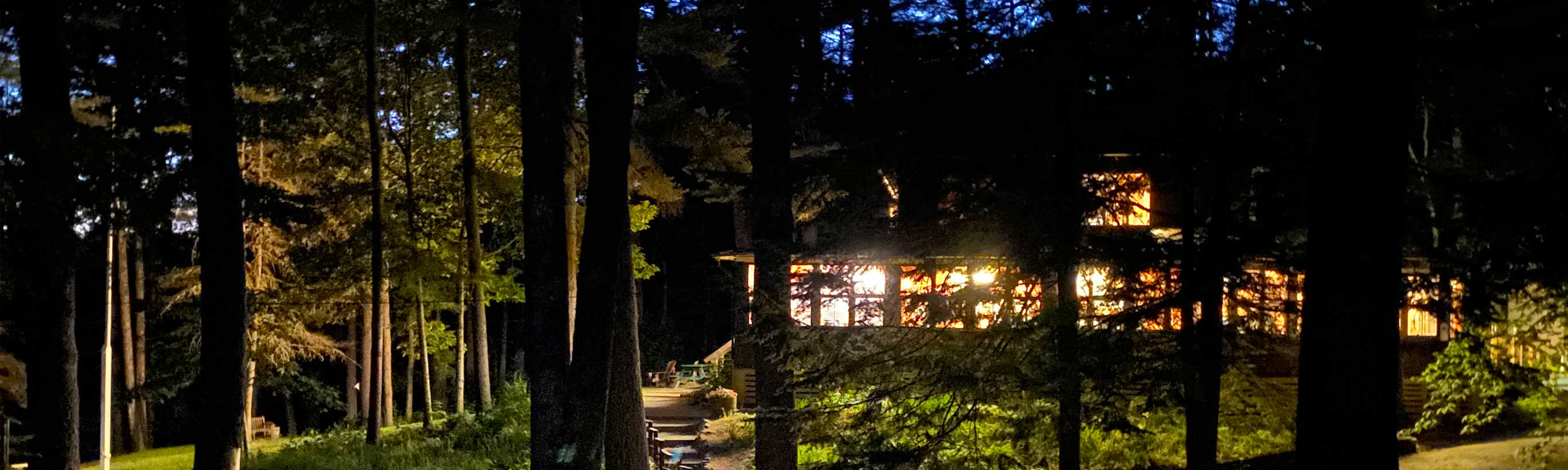A well lit cabin in the woods at night.